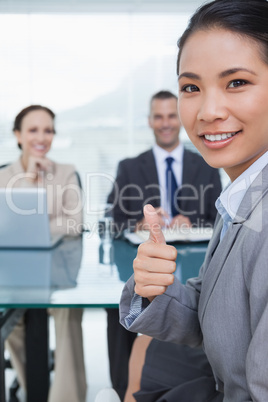 Young pretty applicant showing thumb up after obtaining the job