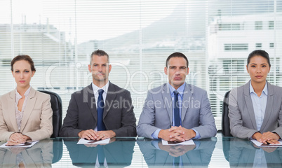 Stern business people sitting straight looking at camera