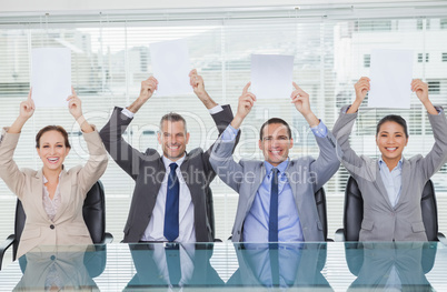 Smiling interview panel holding blank sheets above their head hi