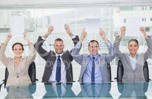 Smiling interview panel holding blank sheets above their head hi