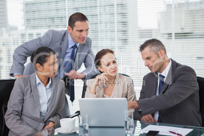 Focused colleagues analyzing documents on their laptop