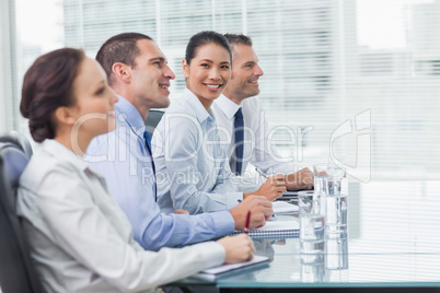 Businesswoman smiling at camera while her colleagues listening