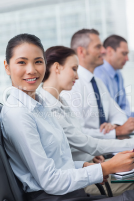 Cheerful employee attending presentation with her colleagues