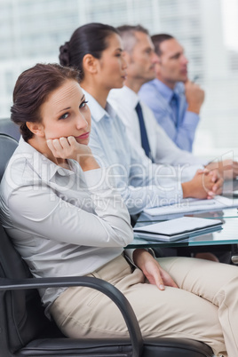 Bored businesswoman looking at camera while attending presentati