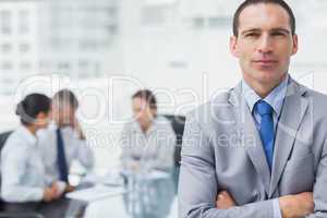 Serious businessman posing with coworkers on background
