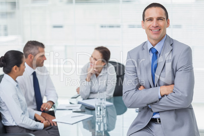 Smiling businessman posing while workmates talking together