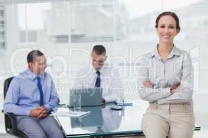 Happy businesswoman posing leaning against the desk