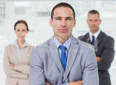 Serious employee posing with his colleagues on background