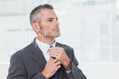 Serious businessman tightening up his tie
