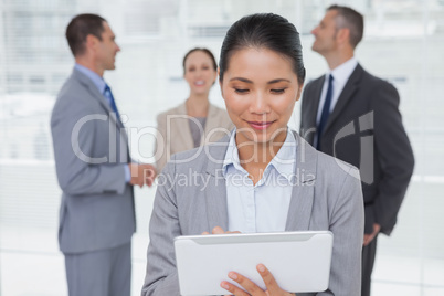 Businesswoman with her tablet pc while colleagues talking togeth