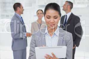 Businesswoman with her tablet pc while colleagues talking togeth