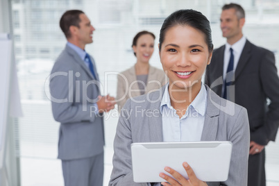 Businesswoman using her tablet pc while colleagues talking toget