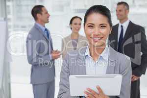 Businesswoman using her tablet pc while colleagues talking toget