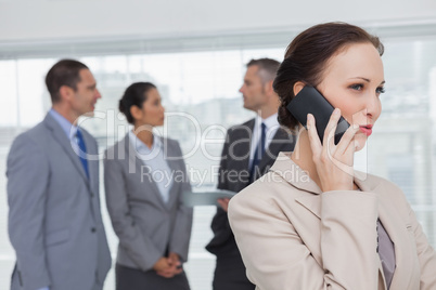 Businesswoman on the phone while colleagues talking together