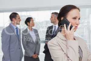 Businesswoman on the phone while colleagues talking together