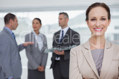 Smiling businesswoman posing while colleagues talking together