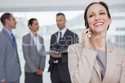 Cheerful businesswoman calling while colleagues talking together