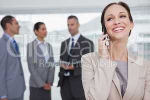 Cheerful businesswoman calling while colleagues talking together