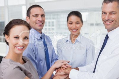 Cheerful work team joining hands together