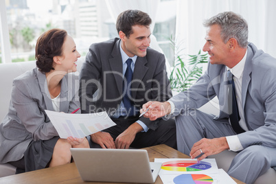 Cheerful business people analyzing financial graphs of their com