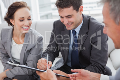 Businessman signing contract while his partner is looking at him