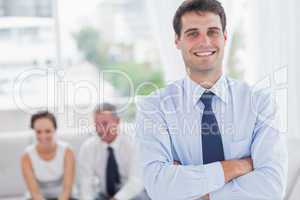 Cheerful businessman posing while his colleagues are working