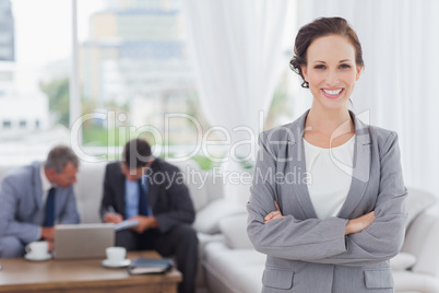 Cheerful businesswoman posing while her colleagues are working