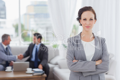 Content businesswoman posing while her colleagues are working