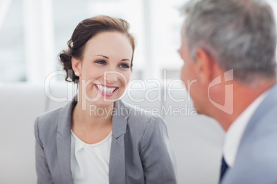 Cheerful businesswoman listening to her workmate talking