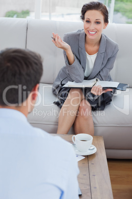 Cheerful businesswoman talking to her colleague while having cof