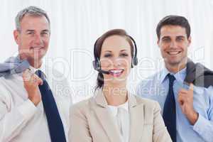 Cheerful call center agent posing with her work team