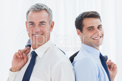 Smiling businessmen posing back to back together while holding t