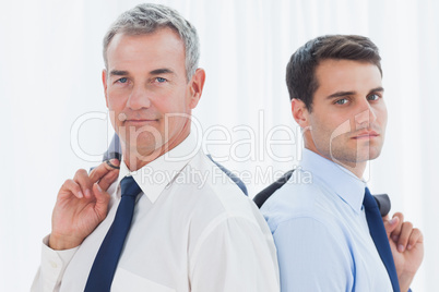 Serious businessmen posing back to back together while holding t