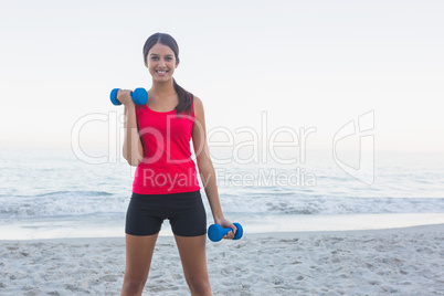 Smiling sporty woman exercising with dumbbells