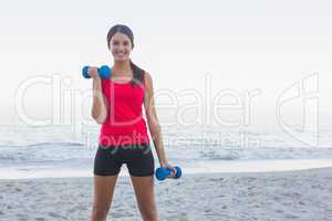 Smiling sporty woman exercising with dumbbells