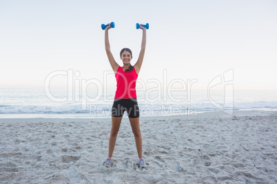 Cheerful sporty woman holding dumbbells