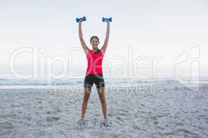 Cheerful sporty woman holding dumbbells