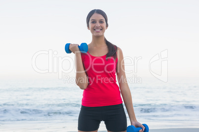 Cheerful sporty woman exercising with dumbbells