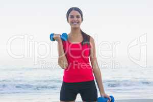 Cheerful sporty woman exercising with dumbbells
