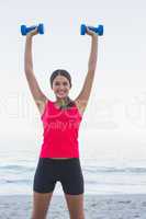 Smiling sporty woman holding dumbbells