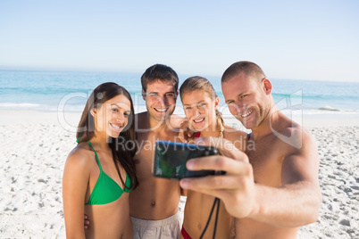 Smiling friends taking pictures of themselves