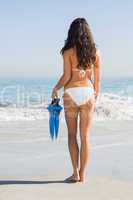 Back of slim young woman holding fins