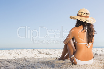 Thoughtful attractive brunette in white bikini sitting