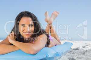 Smiling attractive brunette lying on her lilo
