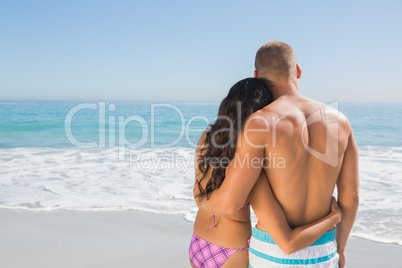 Cute couple hugging while looking at the sea