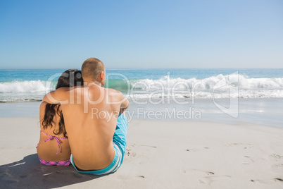 Sexy couple sitting while looking at the sea