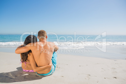 Cute couple sitting while looking at the sea