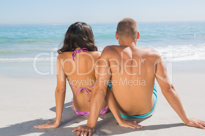 Pretty young couple sitting while looking at the sea
