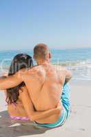 Cute young couple sitting while looking at the sea