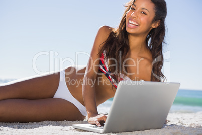 Happy attractive young woman in bikini with her laptop